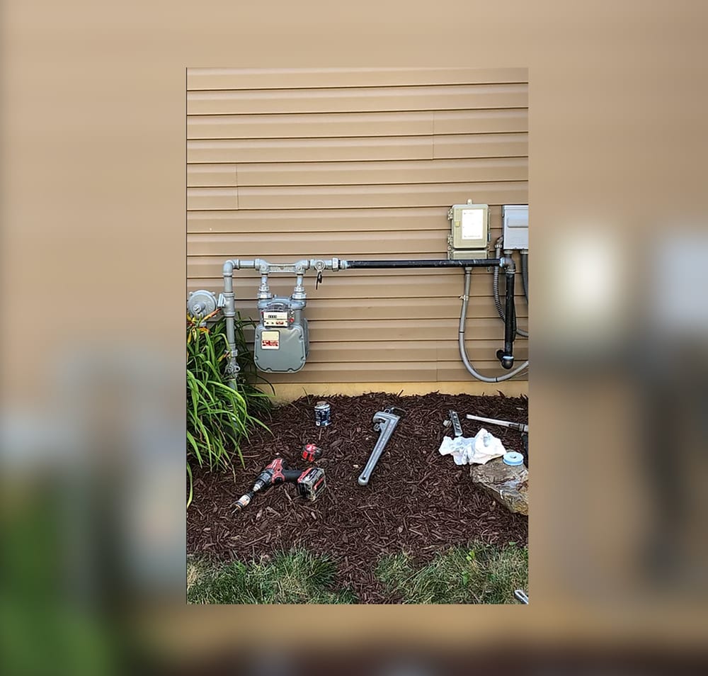 A garden with pipes and tools on the ground.